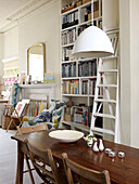 Wooden table in front of bookcase in artist's apartment