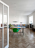 Open glass door leading into interior with herringbone parquet floor and designer furniture