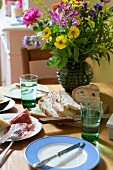 Summer bouquet, bread and salami on table in kitchen-dining room