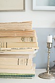 Stacked books and silver candlestick on shelf
