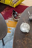 Vintage teapot on coffee table above slip-on sneakers on colourful rug