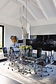 Elegant office chairs around glass table below cylindrical pendant lamp