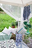 Garden pavilion furnished with bench, cushions and vintage fan on side table