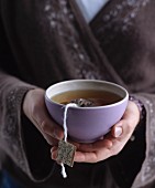 Woman wearing kimono holding bowl of tea in hands