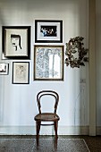 Thonet chair below framed pictures on wall