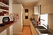 Narrow galley kitchen - classic cream colour scheme with deep red accents