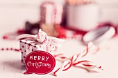 'Merry Christmas' Sprechblase vor rot-weißer Geschenkschachtel und Candies