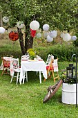 Garden table set for Swedish crayfish party under lanterns hung from tree