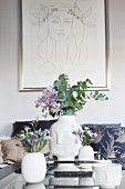 Vasen mit Gesichtern und Blumen unter einem Picasso-Bild