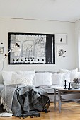 White, vintage-style cushions on grey sofa below black and white artwork