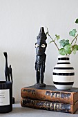 Afrikanische Figur und gestreifte Vase auf zwei alten Büchern
