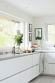 Moderne Küche mit weißen Fronten und Arbeitsfläche aus Edelstahl