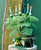 Conifer in pot with green felt cover decorated with baubles & Christmas tree candles