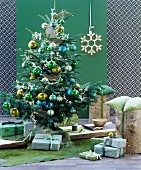 Weihnachtlich dekorierter Raum in Grüntönen mit Christbaum, Geschenken & Baumstammhockern
