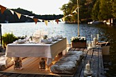 Festlich gedeckter Hochzeitstisch auf Holzterrasse am Wasser