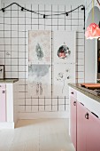 Framed pictures and fairy lights on white-tiled kitchen wall