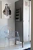 Ghost Stuhl aus transparentem Kunststoff neben Vintage Metallspind, an Wand gerahmtes Bild