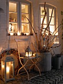 Winterliche Terrasse mit stimmungsvoller Beleuchtung und Blick ins beleuchtete Haus