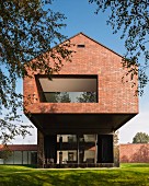 Brick house with loggia in protruding upper storey set in sunny garden