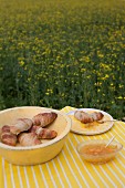 Croissants and jam on table in field of flowering rapeseed