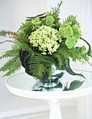 Bouquet of ferns and hydrangeas on glass table