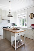 Free-standing island counter in white, wood-clad, country-house kitchen