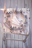 A shiny silver eucalyptus wreath on a white wooden chair