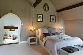 Rustic bedroom with lit pendant lamps flanking double bed and open arched doorway to one side
