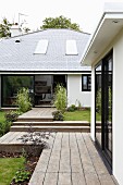 Terrassen und Wege mit Holzdielenbelag vor modernem Wohnhaus