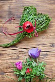 Spring arrangement of bilberry stems tied into love-heart and red anemone