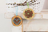 Embroidered wooden discs hung from branch as Easter decorations