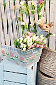 Tulips in embroidered bicycle basket on top of wooden crate painted pale blue
