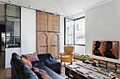 Palettentisch und schwarze Ledersofakombination im Wohnzimmer mit marokkanischem kunsthandwerklichem Holzelement