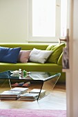 Blick auf hellgrünes Sofa mit Kissen und Plexiglastisch