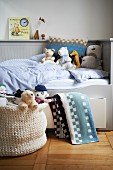 Soft toys on child's bed with pale grey wood cladding and integrated storage drawers