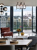 Seating area with coffee table next to glass wall with view of London; dining table in foreground