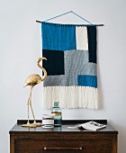 A knitted wall hanging made from a mixed woollen yarn in a block print