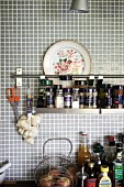 Hellgraue Mosaikfliesen an Wand mit aufgehängtem Gewürzregal in der Küche