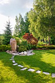 Gardens landscaped with boulders and stepping stones in lawn