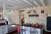 Breakfast bar in open-plan kitchen with grey and white wood-beamed ceiling and stone wall