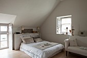Doppelbett mit verschiedenen Kissen im Schlafzimmer mit Dachschräge