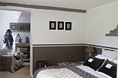 Doppelbett mit Initialien-Kissenbezügen an halbhoch braun getönter Wand, offener Durchgang und Blick auf Schneiderpuppe