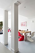 Red and white shell chairs in dining area in open-plan interior
