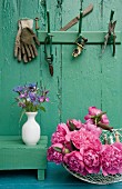 Still-life arrangement of peonies, posy of cornflowers & gardening utensils