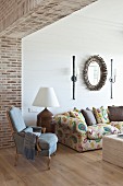 Elegant living area with exposed brickwork in open doorway, antique pale blue armchair and oak parquet floor