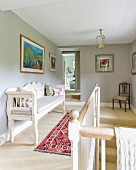 Traditional white bench next to bannister on landing with walls painted pale grey