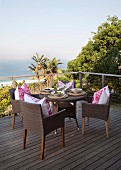 Set round wicker table on wooden deck with view of palm trees and sea