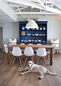 Wooden table, white Eames chairs and blue-painted dresser in renovated country-house interior with Labrador lying on floor
