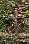 Rusty anchor, metal cross and ornaments against stone wall in garden