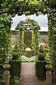View through archway in hedge into topiary garden